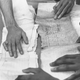 circa 1960: At the Schomburg Center for Research in Black Culture, in New York’s public library, the hands of a group of scholars piece together a ship’s document about a cargo of slaves brought to the United States.
